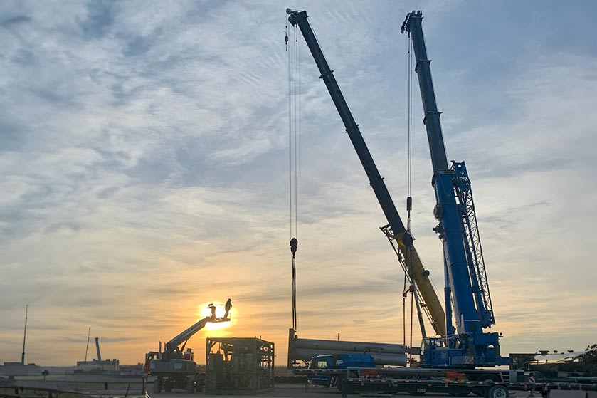 Crane lifting metal beam at construction site